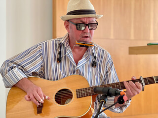 The musician playing blues, acoustic guitar, blues harmonica.
