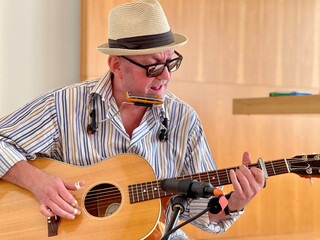The musician playing blues, acoustic guitar, blues harmonica.