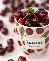 Sweet cherries in a tea mug on pink colored background, closeup view