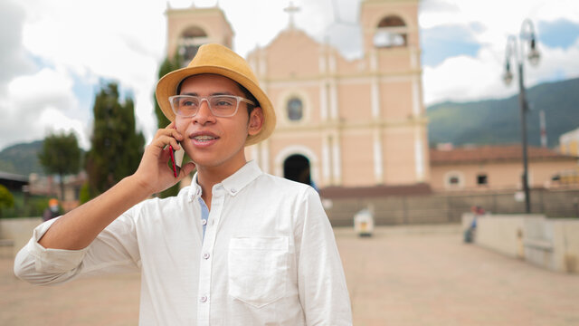 Portrait of a man talking on a cell phone in front of a church of Totonicapan Guatemala.