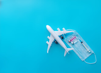 Airplane model with a medical mask on a blue background. Safe travel concept. Opening borders.