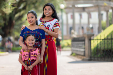 Portrait of two beautiful young women and their little sister wearing a colorful dress from Quiché...