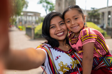 A young mother with her little daughter in a park takes a selfie with the cell phone.