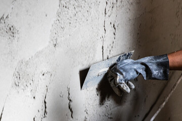 Worker plastering cement mortar on concrete wall with trowel