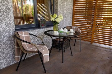 A coffee table with two wicker armchairs on a terrace with a wooden partition.