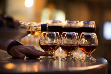 Bar. Celebration. There are many filled glasses on the table. The bartender's hand pours from the...