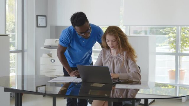 African mentor giving consultation on financial operations to female colleague intern using laptop
