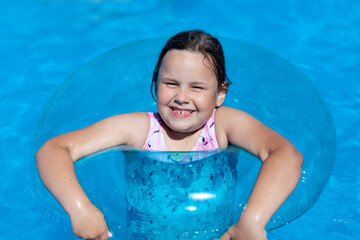 close-up portrait of a smiling five-year-old girl lying on the surface of the water on an inflatable circle, a hot summer day at the sea. 