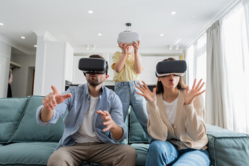 excited family gesturing in vr headsets in living room