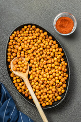 Crunchy roasted chickpeas in cast iron skillet on dark background. Top view, copy space.