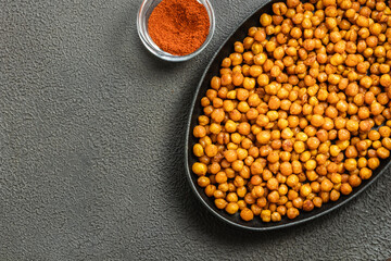 Spicy oven roasted chickpeas in cast iron skillet on dark background. Top view, copy space.