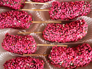Frozen chocolate dipped banana pops on a stick a sprinkle in the shape of pink hearts..Vegan dessert for kids. Banana in chocolate.