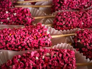 Frozen chocolate dipped banana pops on a stick a sprinkle in the shape of pink hearts..Vegan dessert for kids. Banana in chocolate.