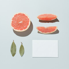 Neatly arranged fruits with leaves and paper. Minimal flat lay on pastel grey background.