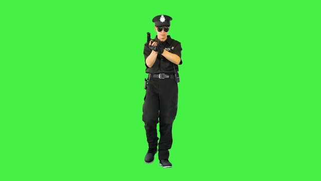 Policeman walks doing some exercices with his gun on a Green Screen, Chroma Key.