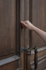 a woman's hand knocking on a closed wooden door, surprise visit, closed, is anyone at home?