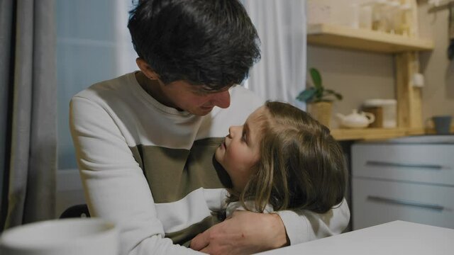 A little girl wA little girl whispers a secret in her dad's ear. A loving father hugs his daughter.hispers a secret in her dad's ear. A loving father hugs his daughter.