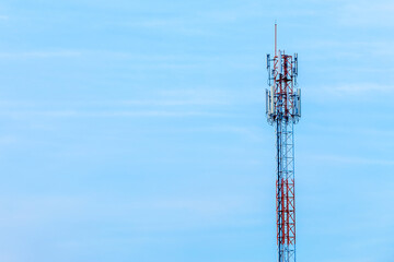 Mobile station receiver antenna tower with fluffy clouds blue sky daylight background.