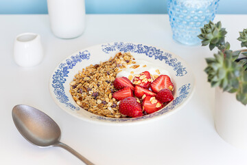 Homemade granola with fresh organic strawberries and yogurt in the vintage plate. Morning breakfast food concept	