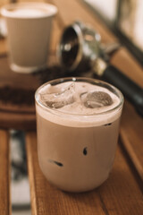 Glass of iced coffee with milk
 and ice in a glass beaker on a wooden background