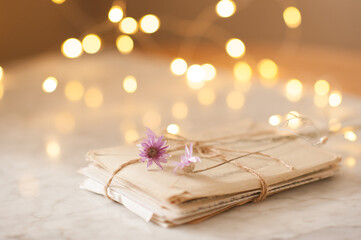 Laced paer handwriten letters with dry flowers over glow lights at background on table in room. Romantic love concept. Snail mail. Valentines Day.