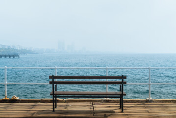 Fototapeta na wymiar Bench on a pier with a view on morning haze over Limassol harbour, Cyprus