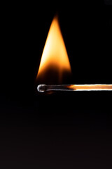 Triangular flame of fire on a match over a black background.