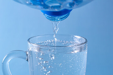 Pouring fresh clean water from a bottle with drops into a glass on the table, the concept of moisturizing health and beauty