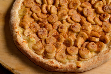 Banana pizza with sugar and cinnamon on wooden board. Brazilian sweet pizza.