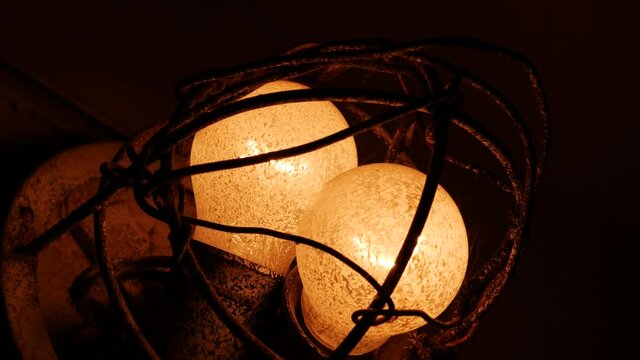 Vintage incandescent light bulbs at the entrance of a residential building. Energy saving concept. Tungsten coil lamps. Outdated technology. Metal protection against damage. E27 base plinth