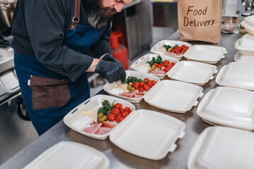 Food in disposable dishes ready for delivery. The chef prepares food in the restaurant and packs it in disposable lunch boxes.