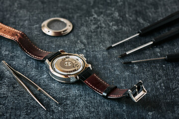 Open wristwatch, tweezers and screwdrivers, watch repair concept, close up, shallow depth of field - obrazy, fototapety, plakaty