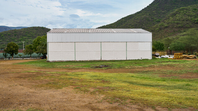 almac&eacute;n para guardar y fabricar productos, dentro de un campo cerca de una colina con un cielo muy bonito