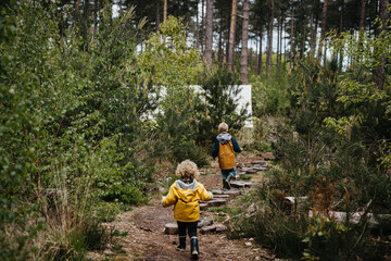 Brother and sister following a trail in the woods