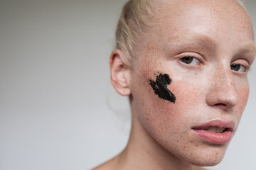 Young model with black scrub on face