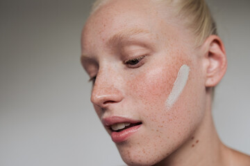 Freckled model with white clay mask on her face
