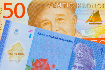 A macro image of a gray and orange fifty kronor note from Sweden paired up with a blue, plastic one ringgit bank note from Malaysia.  Shot close up in macro.