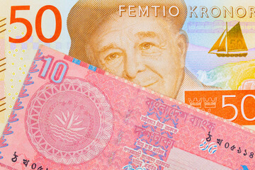 A macro image of a gray and orange fifty kronor note from Sweden paired up with a red ten taka bank note from Bangladesh.  Shot close up in macro.
