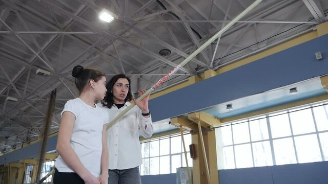 sports kid.Girl at pole vault training at a sports club. Woman trainer prepares and teaches children's sports