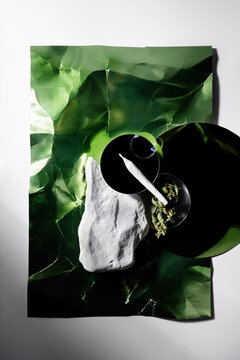 Artistic still life cannabis set with joint and marijuana bud on green background