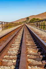 Closeup of railroad tracks converging in the distance by the ocean