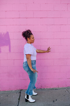 Woman dancing in front of pink outdoor wall