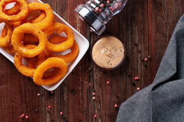 Delicious homemade crunchy fried onion rings with spicy sauce. Top view. Copy space