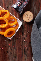 Delicious homemade crunchy fried onion rings with spicy sauce. Top view. Copy space