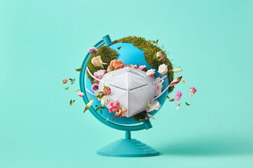 Globe with green moss, flowers and protective medical mask