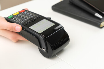 Female hand holding pos terminal for contactless payment.