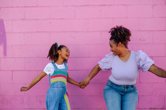 Dancing mom and girl in front of pink wall