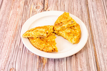 Butterfly omelette. Spanish omelette with eggs on white plate and reddish wooden table.