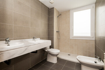 Apartment bathroom with gray and beige tiles with white marble countertop and gray veins.