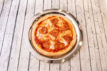 Pizza sencilla con queso mozzarella, lonchas de chorizo picante con oregano y masa de harina de trigo.